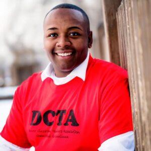 headshot of newly elected Denver school board member Tay Anderson wearing a bright red tshirt with DCTA, Denver Classroom Teachers Association
