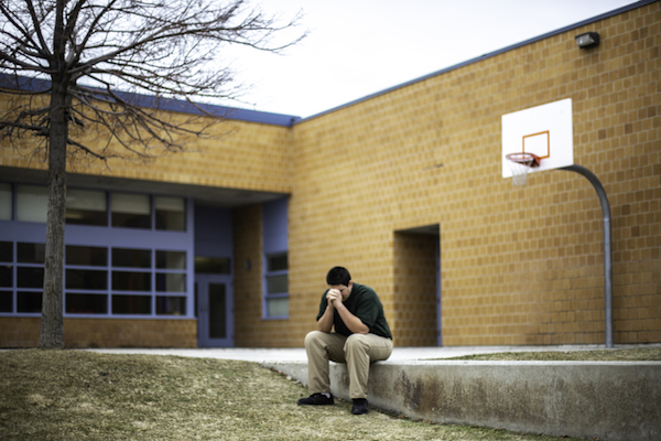 A student in Utah sits alone outside his classroom